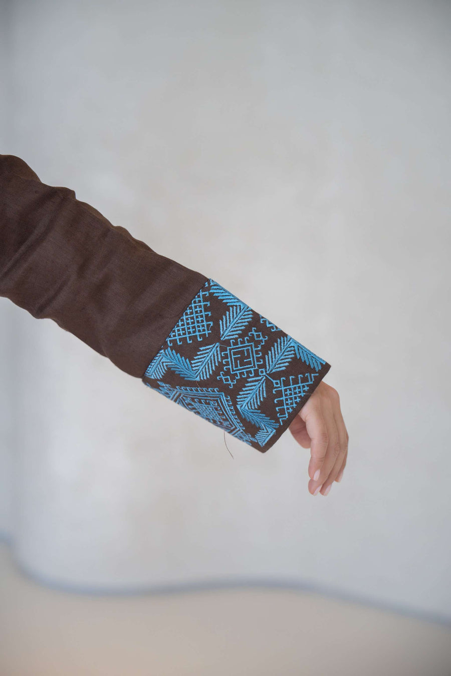 Brown abaya sleeve with intricate vertical turquoise blue embroidery and folded faux pocket detail abaya in a calm brown