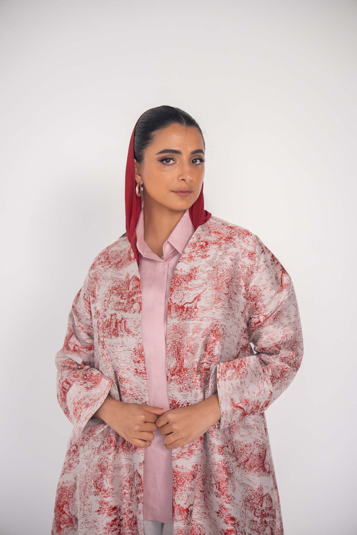 Woman wearing Cherry Haneen jacquard abaya with red Toile de Jouy pattern on off-white fabric and tailored sleeves