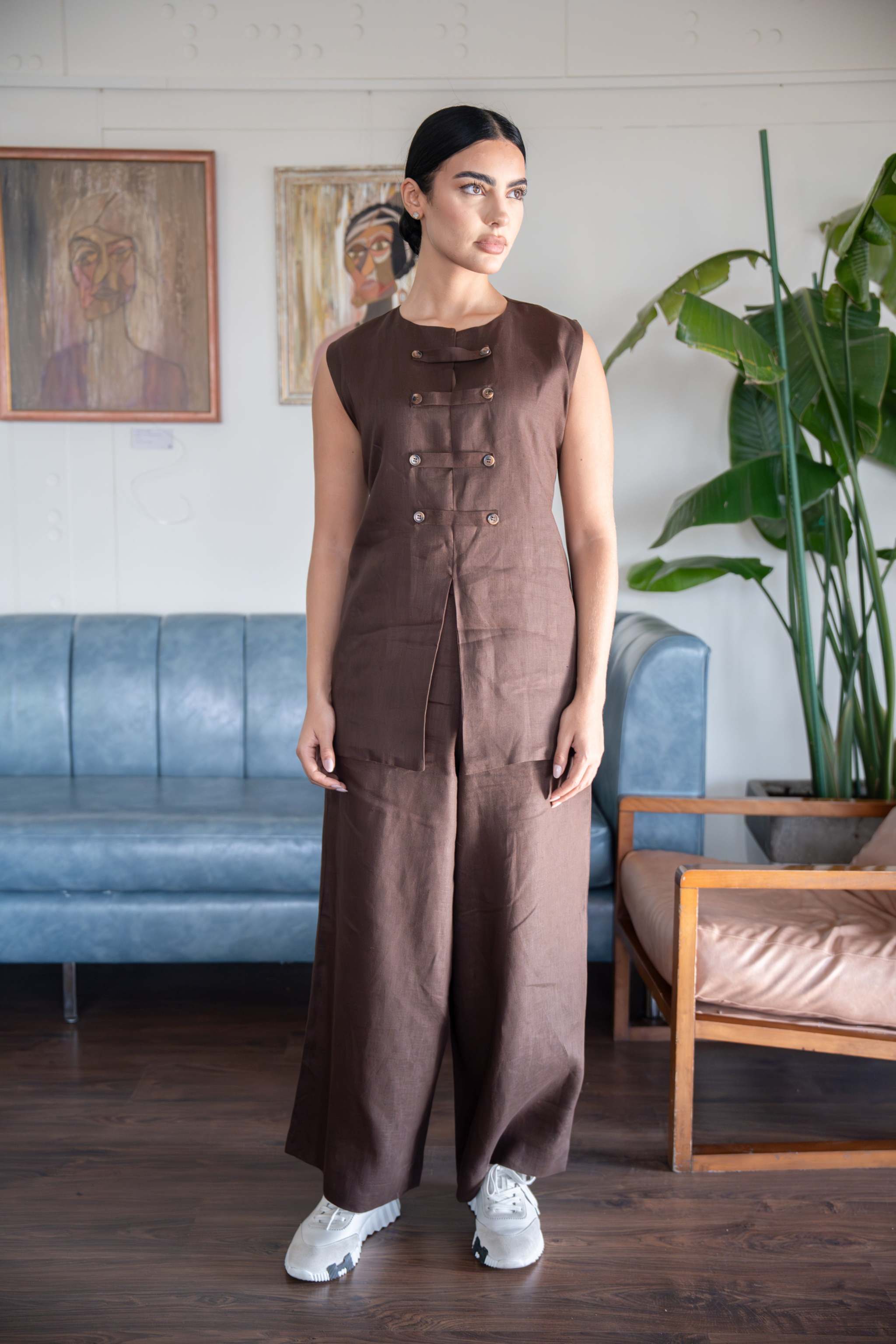 Sleeveless brown blouse with asymmetric button detailing and structured cut worn with matching wide-leg pants