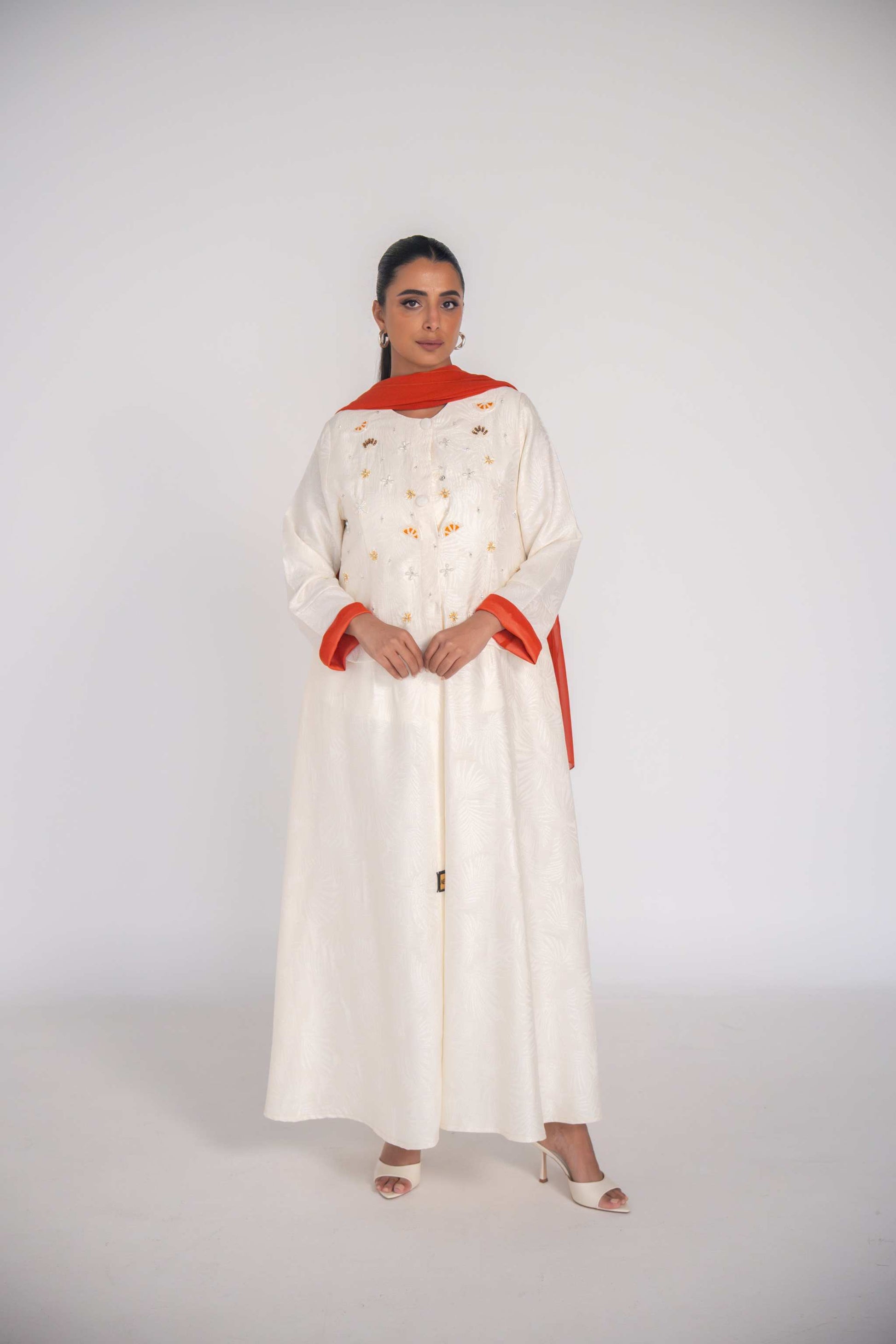 Elegant abaya made of textured jacquard fabric with hand-embroidered orange slice motifs and orange chiffon lining
