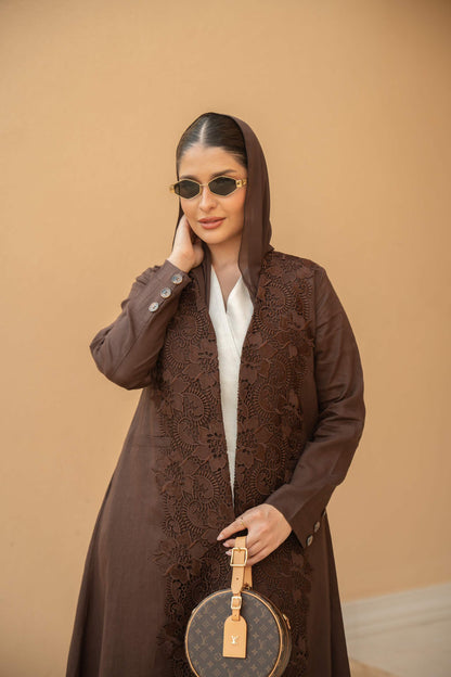 Woman wearing deep mocha brown Mocha Bloom Abaya with intricate floral embroidery and open front style holding a round handbag.