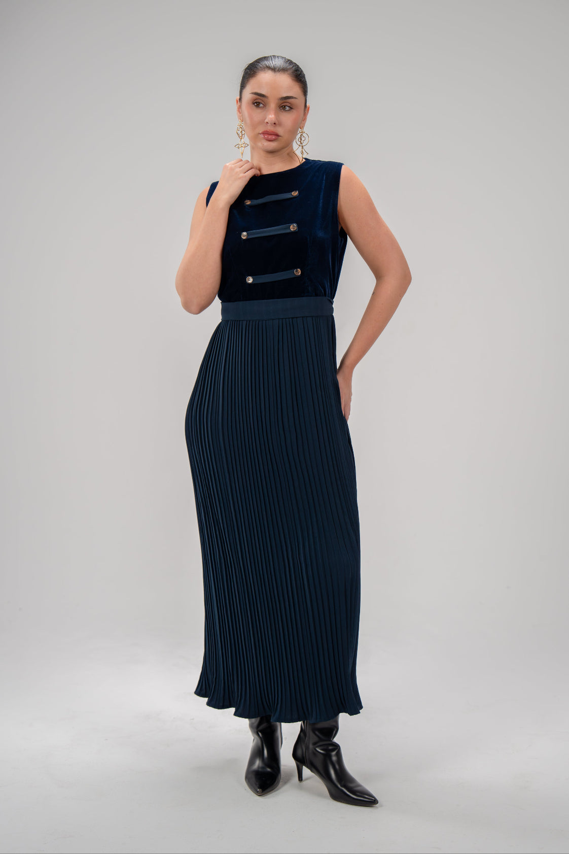 Woman wearing a refined navy blue velvet top dress with pleated crepe skirt and button details