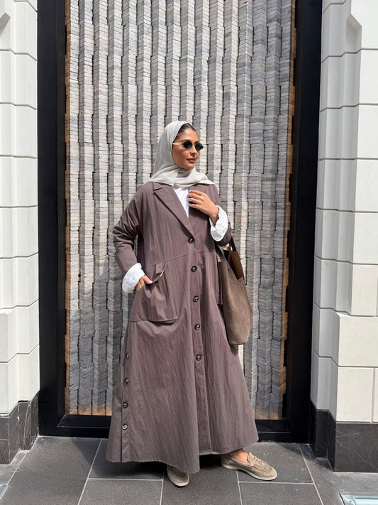 Woman wearing a long trench coat with lining on sleeves and buttons down the front standing outdoors