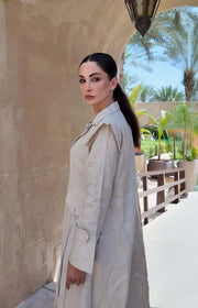 woman wearing a beige linen abaya with trench-style silhouette and matching sheila holding a brown handbag - beige abaya