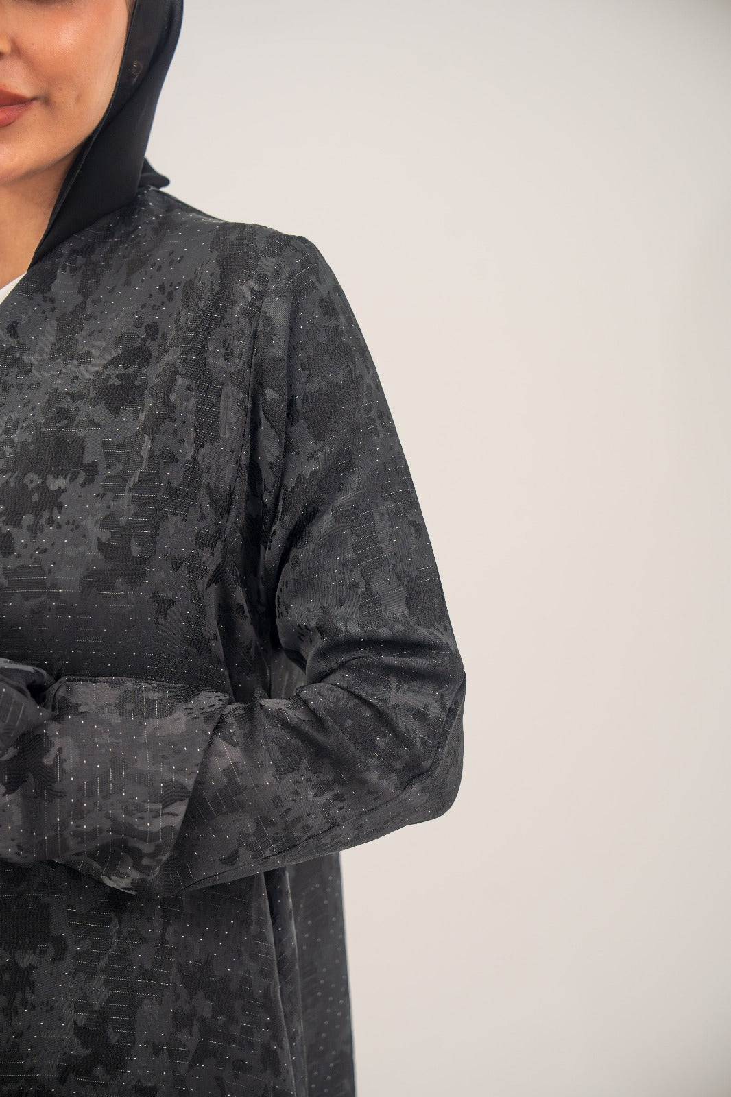 Black silk Ashmere abaya with subtle abstract woven pattern and light shimmer, open-front design with relaxed structured fit.