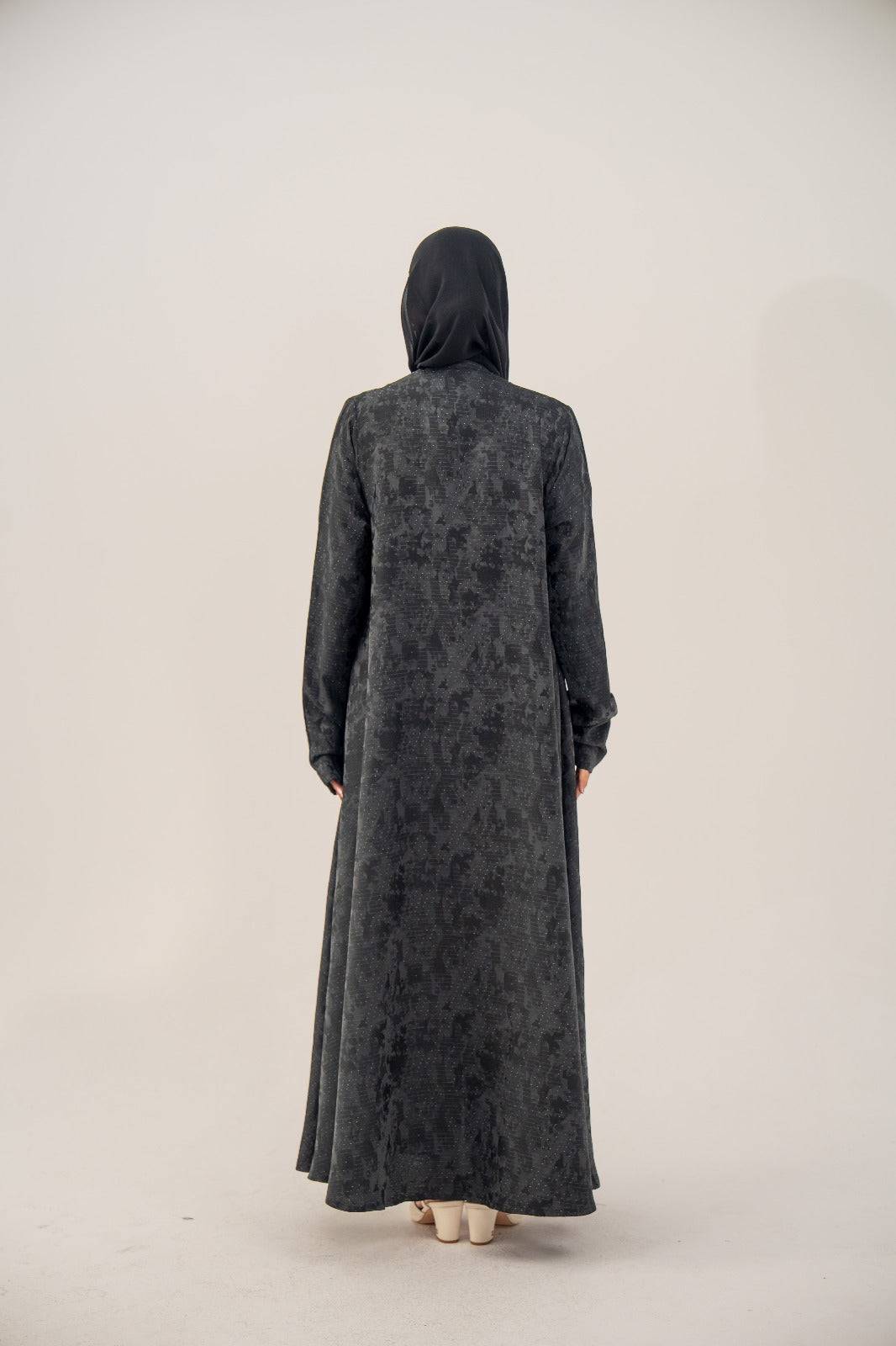 Back view of a black silk Ashmere abaya with subtle abstract woven pattern and relaxed structured cut, featuring a soft shimmer and charcoal gray finish.